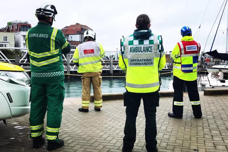 A photo of 4 people in emergency uniform looking out over a harbour.