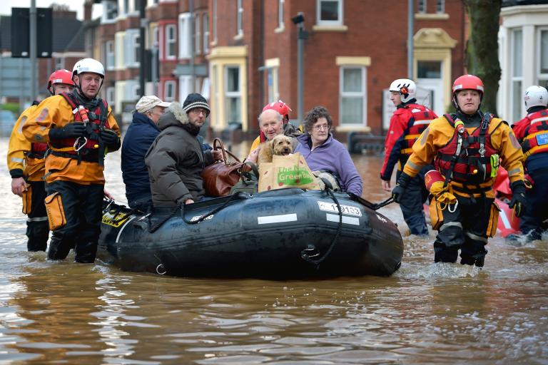 Rescuers moving an inflatable boat along a flooded street in Cumbria.